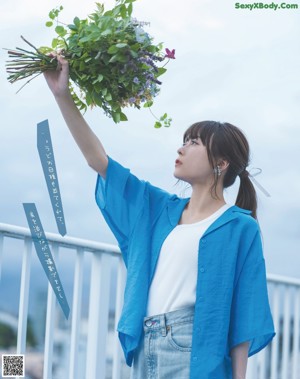 A woman sitting on top of a wooden table next to a plant.