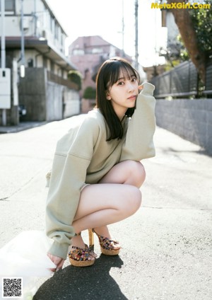 A woman in a black and white dress leaning against a wall.