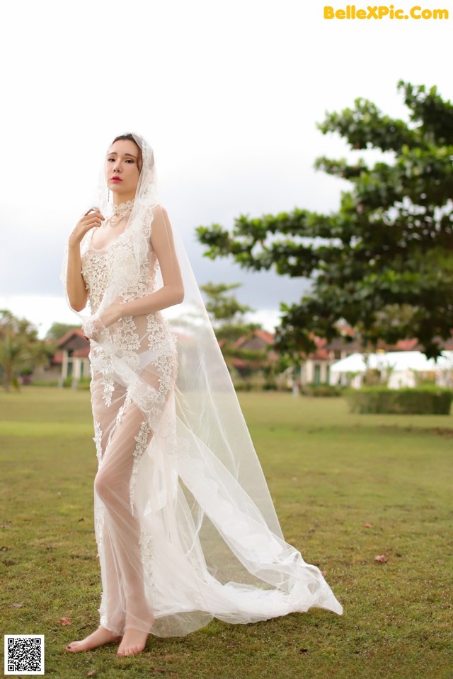 A woman in a wedding dress standing in a field.