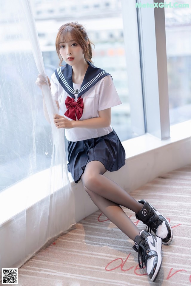 A woman in a sailor outfit sitting on a window sill.