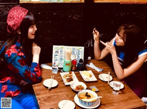 A couple of women sitting at a table eating food.