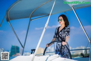 A woman sitting on the deck of a boat in the water.