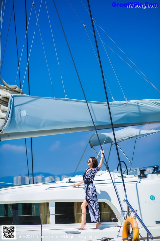 A woman standing on the deck of a sailboat.