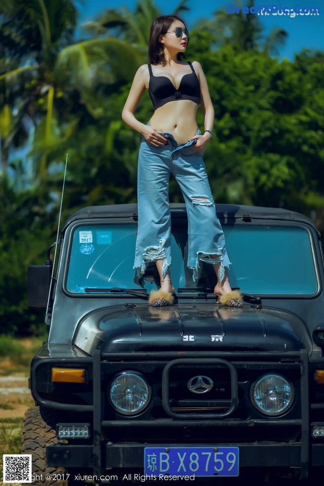 A woman standing on top of a black jeep.