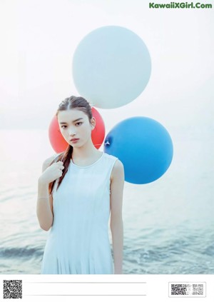 A woman in a blue top and blue shorts is standing on a pier.