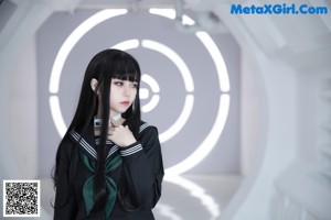 A woman in a school uniform sitting on a white wall.