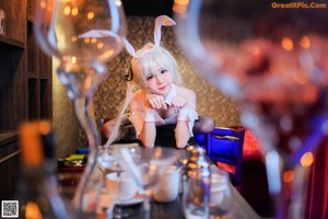 A woman in bunny ears sitting at a bar with a glass of wine.