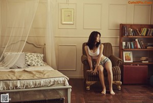 A woman sitting on a window sill next to a window.