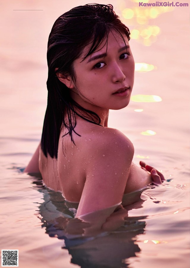 A woman in the water with her back to the camera.