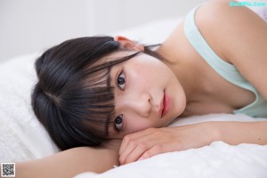 A young woman standing in a bedroom next to a bed.