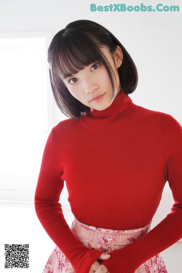 A woman in a red turtleneck sweater is posing for a picture.