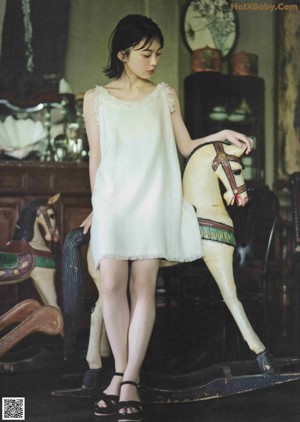 A woman in a white dress standing next to a horse.
