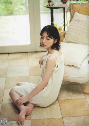 A woman sitting on the floor in front of a couch.