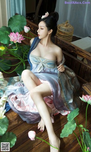 A woman sitting on a wooden floor next to a plant.