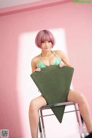 A woman in a green bikini sitting on a green chair.
