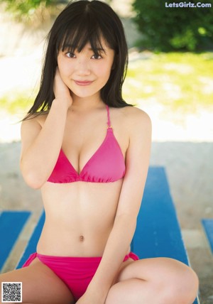 A woman in a bathing suit and a hat posing in the water.