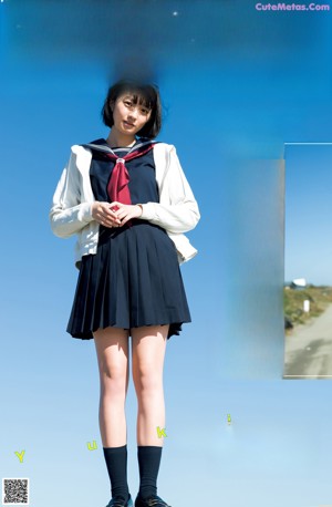 A woman in a school uniform standing on a beach.