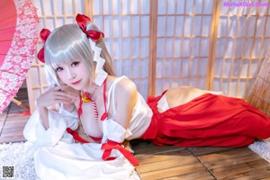 A woman in a red and white dress sitting on the floor.