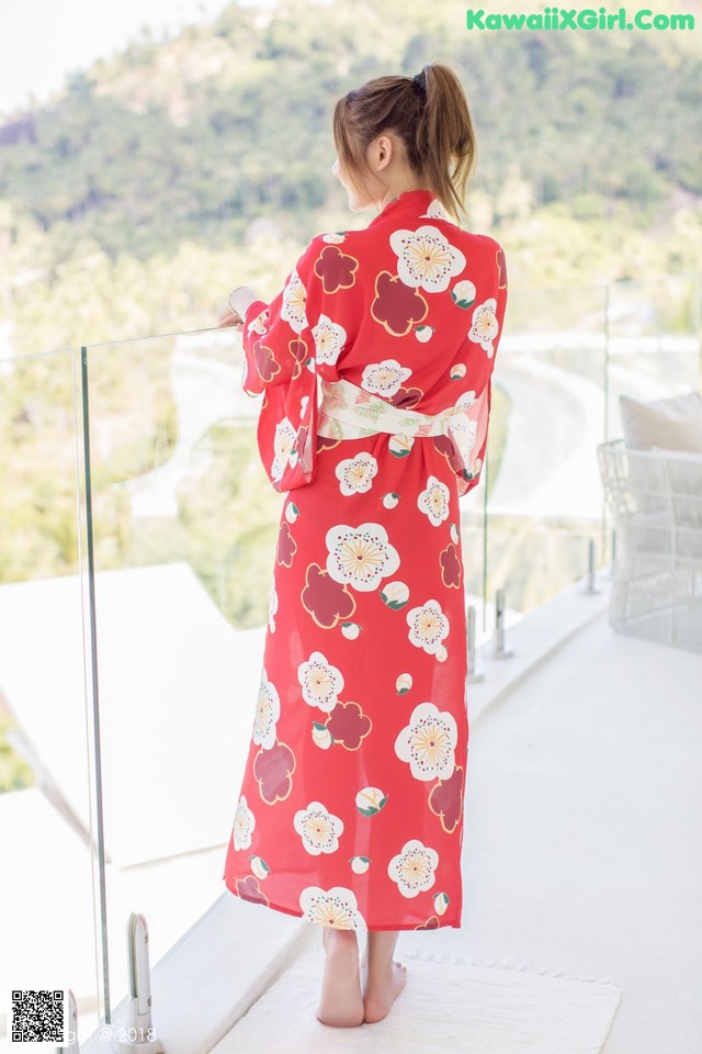 A woman in a red kimono standing on a balcony.